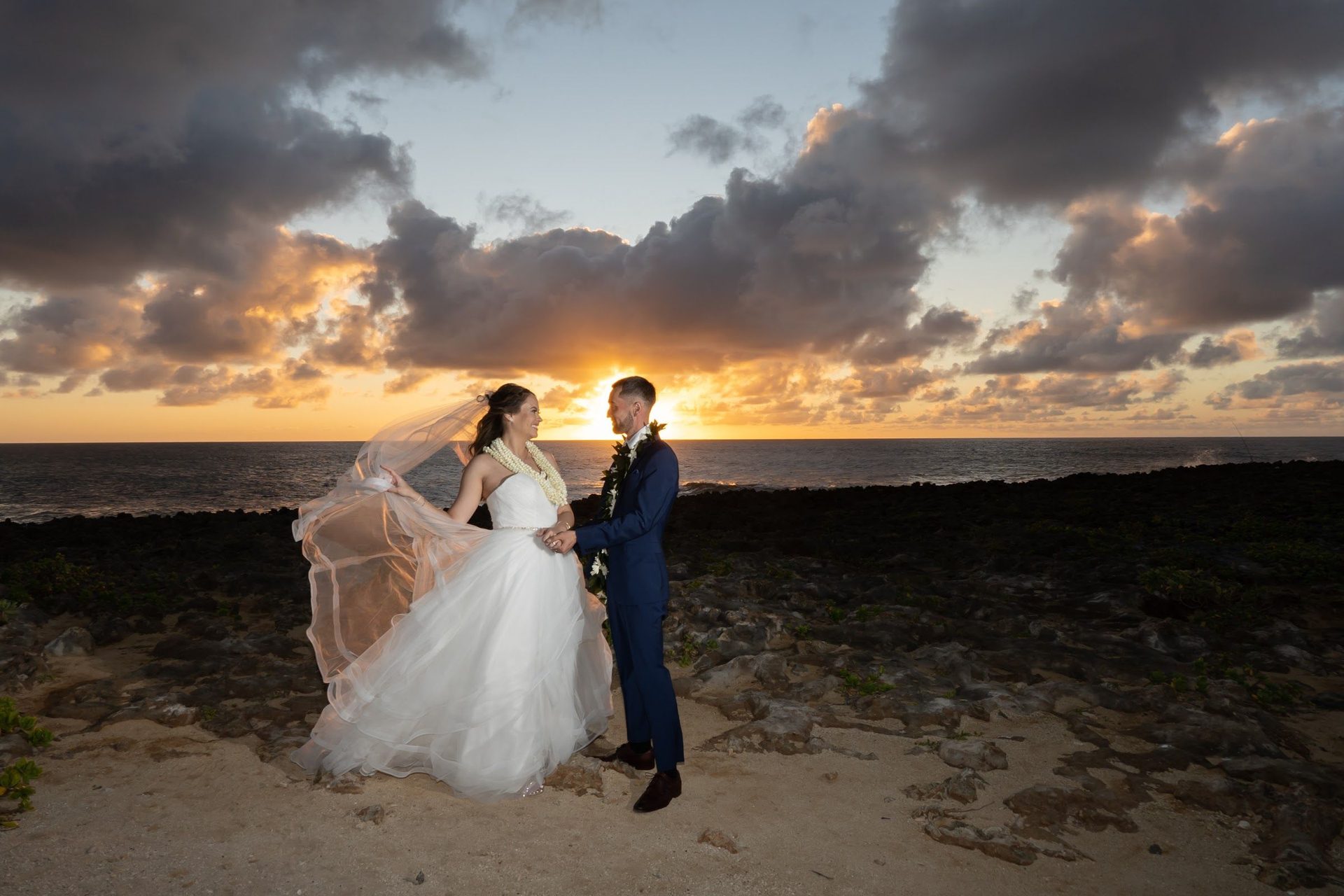 Newlyweds on the beach at sunset under an orange sky