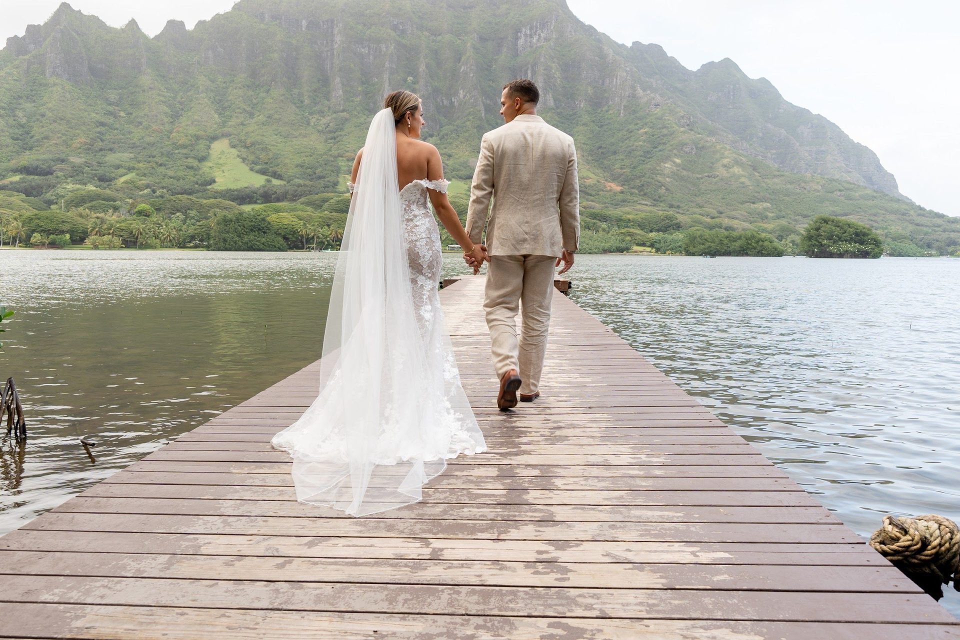 Couple walking together on a pier with the Ko'olau mountains behind them