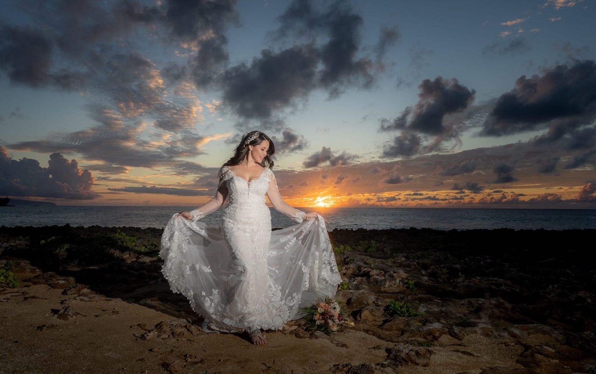 Bride alone on the beach at sunset with her veil catching the wind